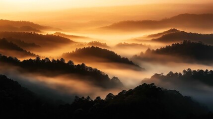 Scenic view of mountains covered with mist during golden sunrise, creating a layered and ethereal landscape.