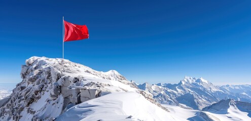 Red flag on snow-covered mountain peak against blue sky