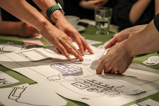 Collaborative Storyboarding in Creative Workshop. Participants engage in a hands-on activity, arranging cut-out illustrations and speech bubbles on a storyboard template during a creative workshop.