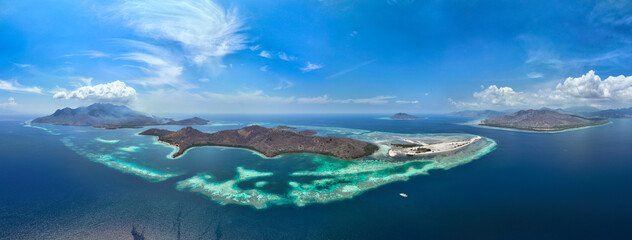 Naklejka premium A beautiful and healthy coral reef surrounds a volcanic island off the coast of Flores, Indonesia. This area, in the Lesser Sunda Islands, is known for its high marine biodiversity.