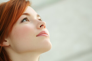 Fototapeta premium A young woman gazes upward with a thoughtful expression in a bright, serene environment