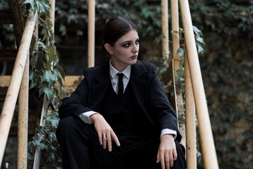 Portrait of stylish and attractive Caucasian young brunette woman in a suit, posing on the street...
