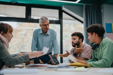 University students engage in a collaborative project with the guidance of a senior professor. The scene reflects teamwork, learning, and academic support in a modern educational environment.