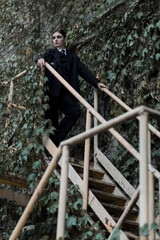 Portrait of stylish and attractive Caucasian young brunette woman in a suit, posing outdoors on iron stairs. Beauty, fashion, style. Well-dressed model.