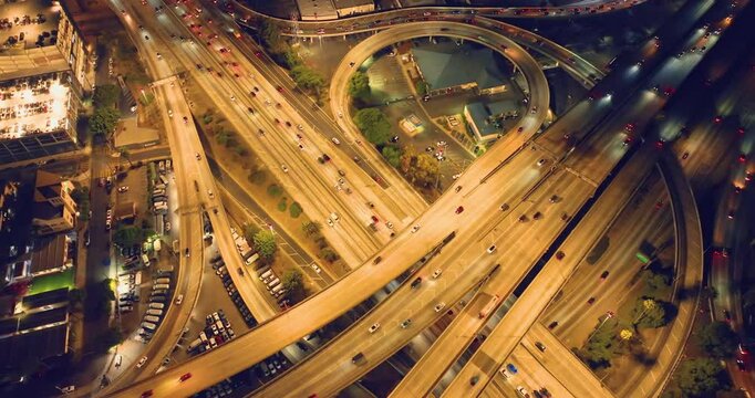 Night illumination of elevated multilevel traffic junction. Modern development of backlighted roads and current new infrastructure in Los Angeles. Aerial drone point of view.