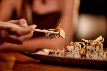 Close-Up of Hand Picking Sushi with Chopsticks in Restaurant