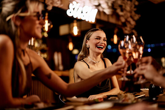 Group of Friends Toasting with Wine in a Cozy Restaurant Setting