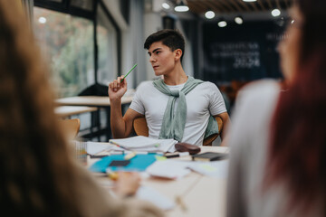 A focused student in a classroom setting, holding a pen and actively engaging in a discussion with...