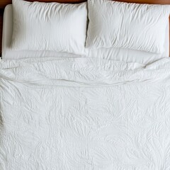 A neatly arranged white bed with pillows and a textured blanket.