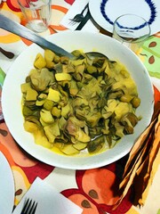 Pastel of a bowl of salad with artichokes and potatoes just served at the table.