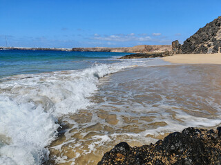 Papagayo beach with fine sand and clear water with waves on a sunny day at the Atlantic Ocean, Lanzarote