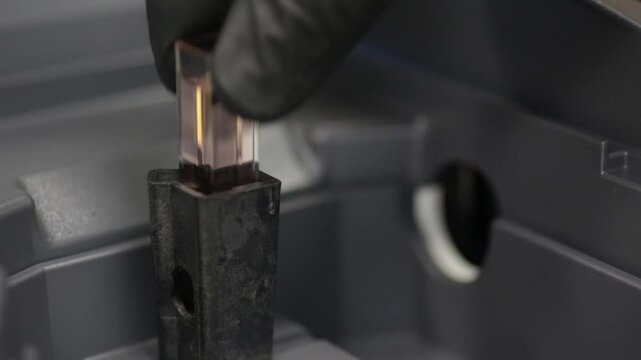 Placing a cuvette into a spectrometer to measure absorbance.