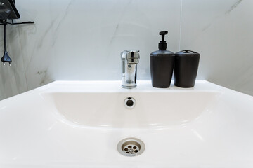 The stylish bathroom features a contemporary sink with a sophisticated faucet and two soap dispensers, ensuring hygiene and a delightful handwashing experience for all users