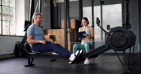 Personal Trainer In Gym Showing Rowing Machine © Andrey Popov