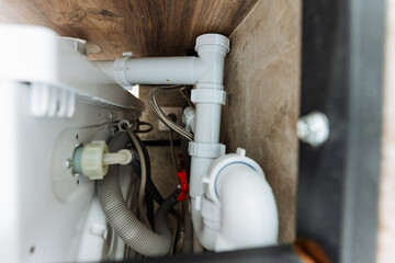 This image shows a detailed closeup of a pipe located under a kitchen sink, highlighting various plumbing components and connections essential for proper kitchen functionality