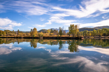 Mirror reflection of the fall colors trees in calm water. Location is Wolf Creek, Idaho
