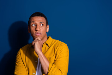 Portrait of nice young man look empty space wear yellow shirt isolated on dark blue color background