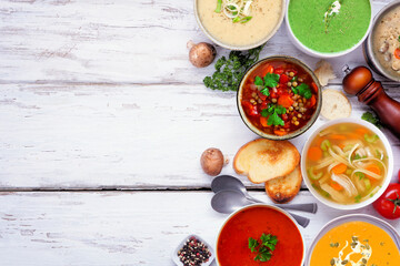 Collection of delicious homemade soups. Top view side border on a white wood background. Warm and cozy food concept.