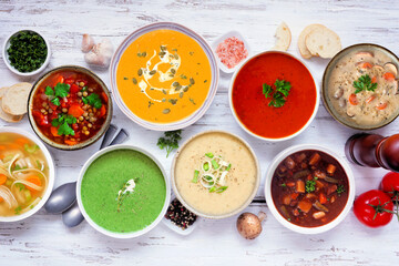 Variety of delicious homemade soups. Above view corner border on a white wood banner background....