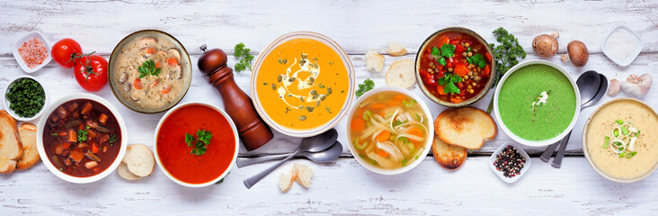 Variety of delicious homemade soups. Above view table scene on a white wood banner background. Warm and cozy food concept.