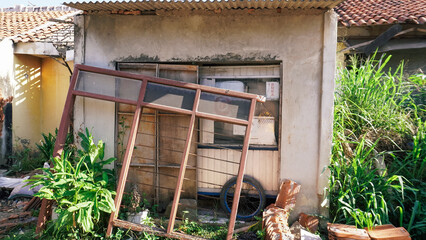 Abandoned home with broken roof tiles and overgrown garden. Decaying structure with signs of neglect
