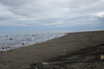 Waves on a sandy beach under cloudy sky