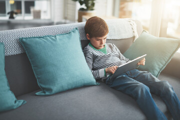 Couch, games and boy child on tablet for cartoon streaming online for movie, internet or video on technology. Notepad, house or bored male kid on touchscreen for learning development or playing alone