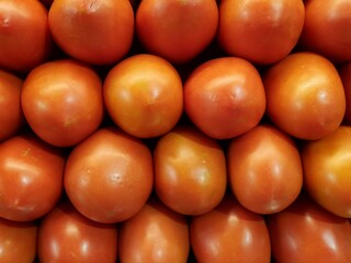 Shiny red tomatoes right next to each other. Seen up close.