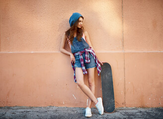 Woman, skateboard and wall in city, street and thinking with fashion, reflection or break for action sport. Girl, person and skater with memory, perspective and streetwear on sidewalk in Canada