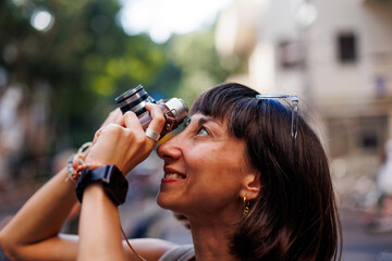 Girl walking around the city and taking pictures with a camera. young girl with a film camera in...