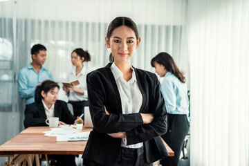 Portrait of happy young asian businesswoman looking at camera with motion blur background of business people movement in dynamic business meeting. Habiliment