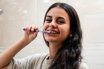 Dental care: young girl with braces brushing her teeth