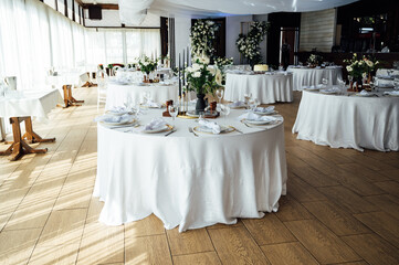 Luxurious restaurant. Luxurious interior, white tables, serving dishes and glasses for guests