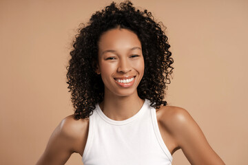 Smiling young African American woman posing in studio looking at camera, isolated on beige