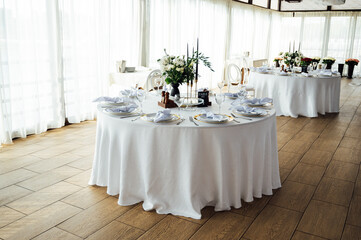 Luxurious restaurant. Luxurious interior, white tables, serving dishes and glasses for guests