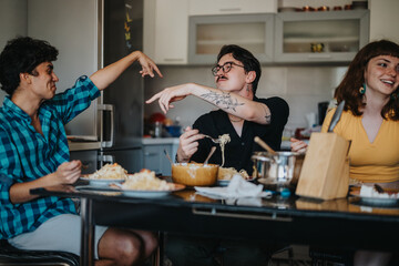 A group of friends sharing a meal together, laughing and engaging in conversation at the dining table in a cozy kitchen environment.