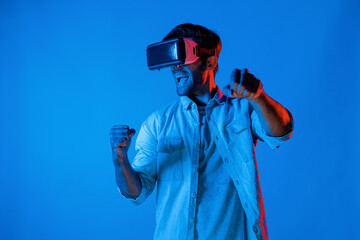 Smart man wear virtual goggle while move driving car hand gesture. Caucasian teenager using futuristic digital technology to enter virtual world while standing at colorful neon background. Deviation.