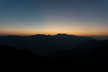 Beautiful dawn view just before sunrise. Horizon and sky looks as orange hues paint the sky.Layered mountains and morning mist create a serene and peaceful sunrise moment in a village of Uttarakhand. 