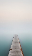 Fototapeta premium A pier stretches across a foggy blue body of water.