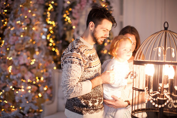 happy family, mother, father and little daughter stands at the Christmas tree and celebrate Christmas and New Year