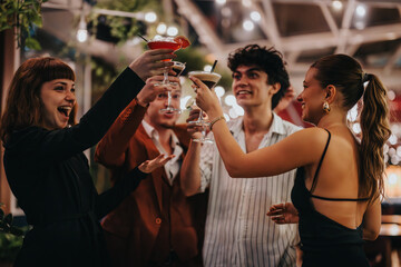 A joyful group of friends toasting with cocktails at an evening party, exuding happiness and...