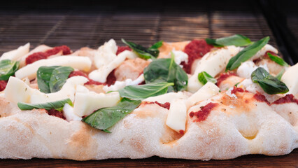 A pizza with a lot of toppings including cheese, spinach, and tomatoes. The pizza is on a wooden cutting board