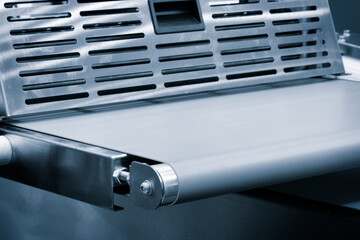 A conveyor belt with a silver color and a black handle. The conveyor belt is made of metal and is used for transporting items