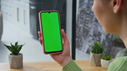 Woman hands watching greenscreen cellphone at home desk closeup. Lady online