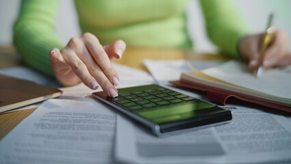 Unknown lady working calculator counting company expenses income indoors closeup