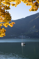 Picturesque autumn scenery with a mountain lake and a sailing boat in the Austrian Alps
