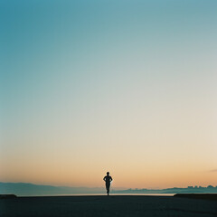 A lone runner in a field during sunset