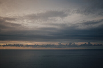Raining sunset sky over the Atlantic Ocean, Tenerife. Minimalism. Misty dusk in the sea. Dramatic view. Tranquil empty landscape with soft golden gray sky. Natural gloomy weather.