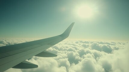 Obraz premium Airplane wing soaring above a field of fluffy white clouds, with a bright sun shining in the blue sky.
