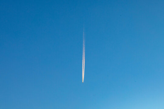 contrail of an aircraft in morning light at blue sky